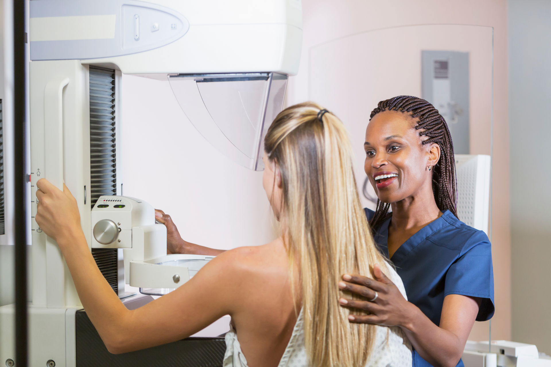 A nurse assisting and reassuring a woman during her medical exam while giving her tips on preventive care