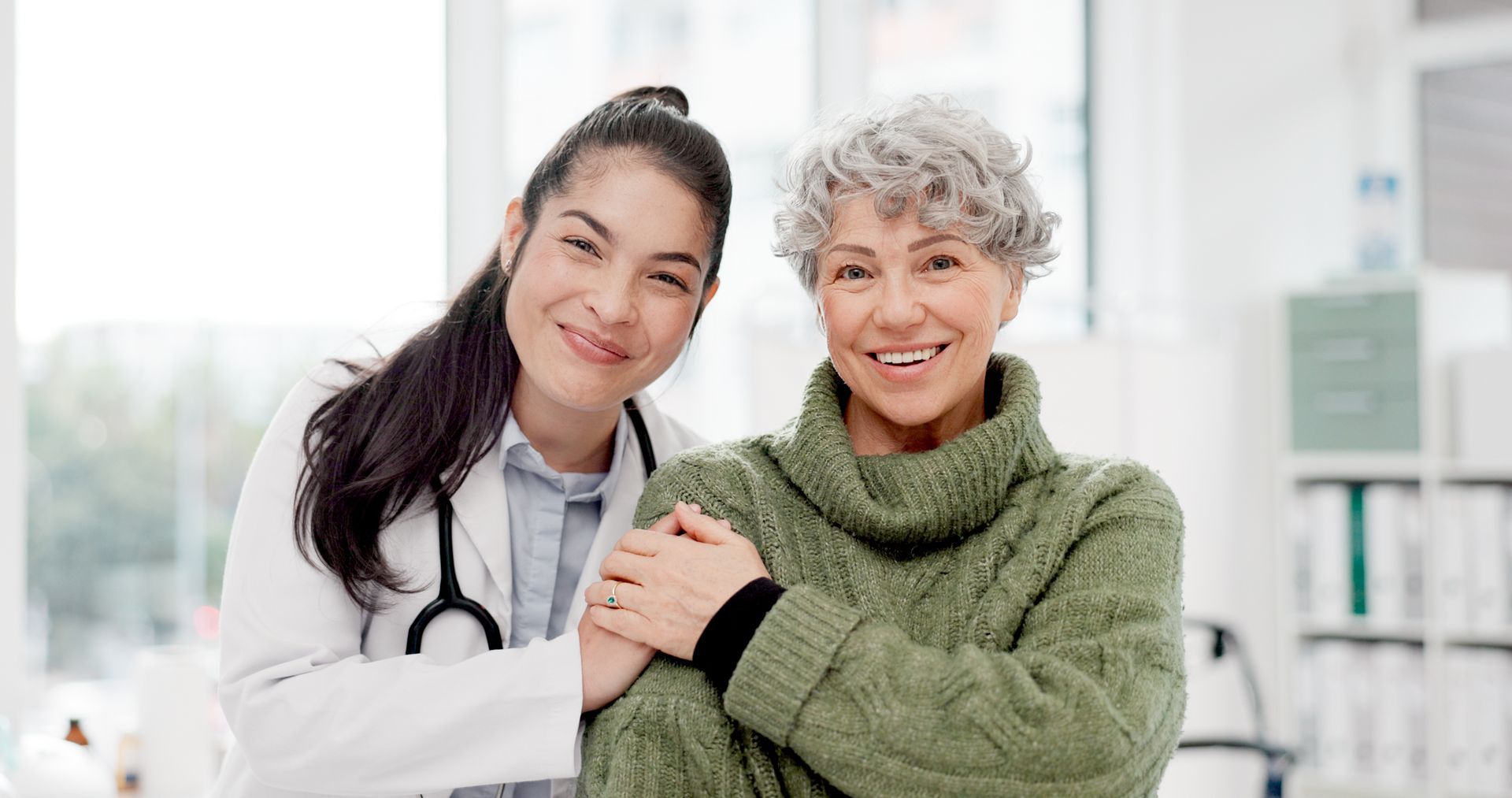 A primary care doctor and her patient smiling at the camera.