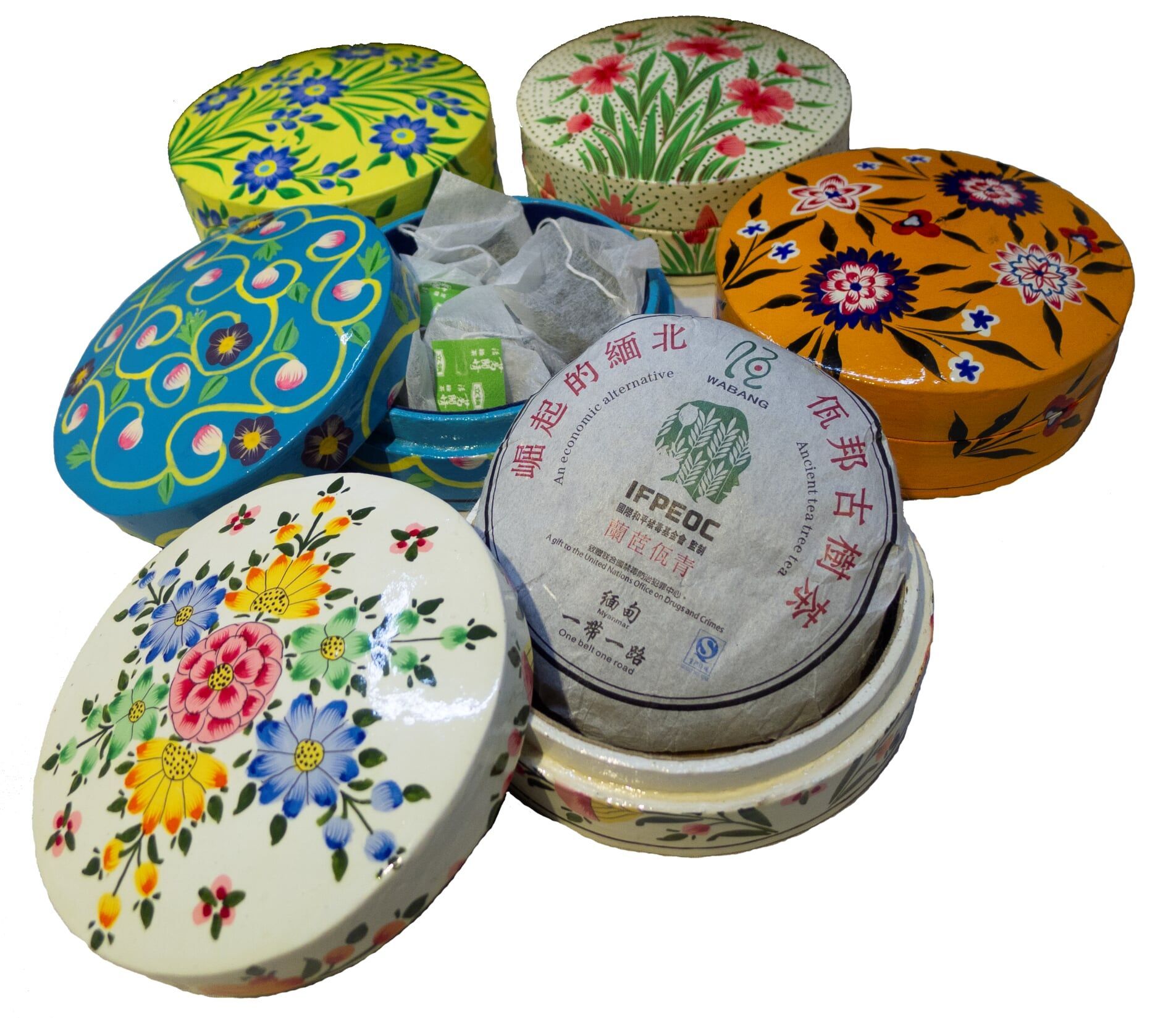 Colorful tea boxes with floral designs, one open with tea cakes and bags.