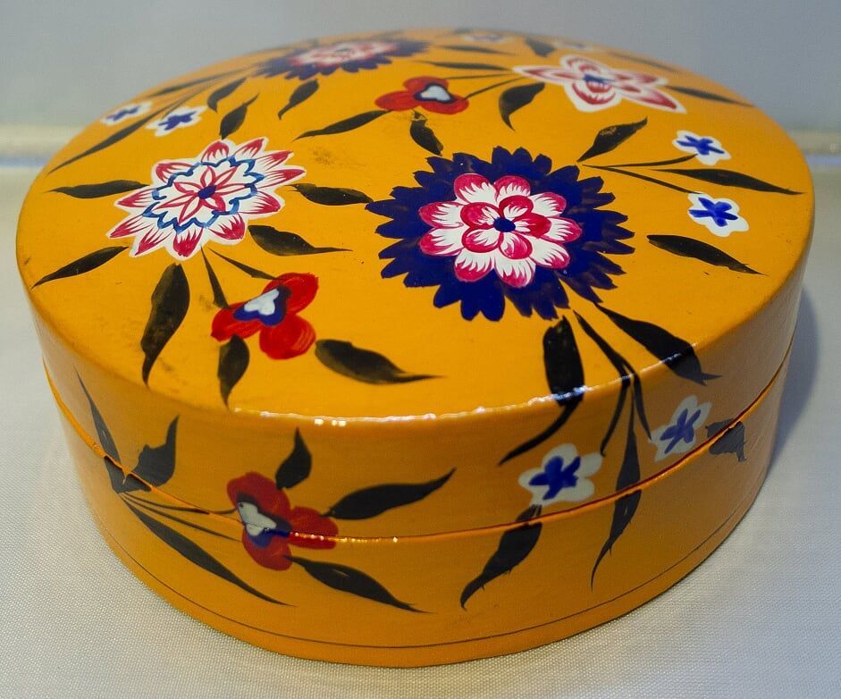 Yellow, round, hand-painted box with floral design in red, blue, and white.