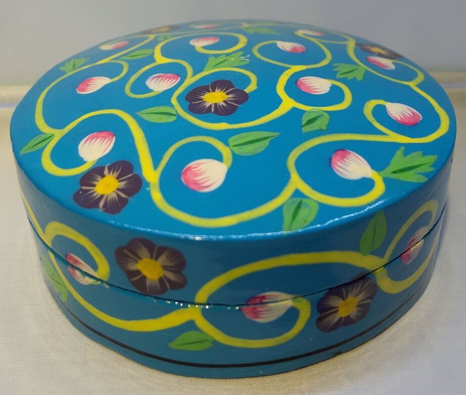 Blue wooden box with yellow vines, purple flowers, and pink petals.