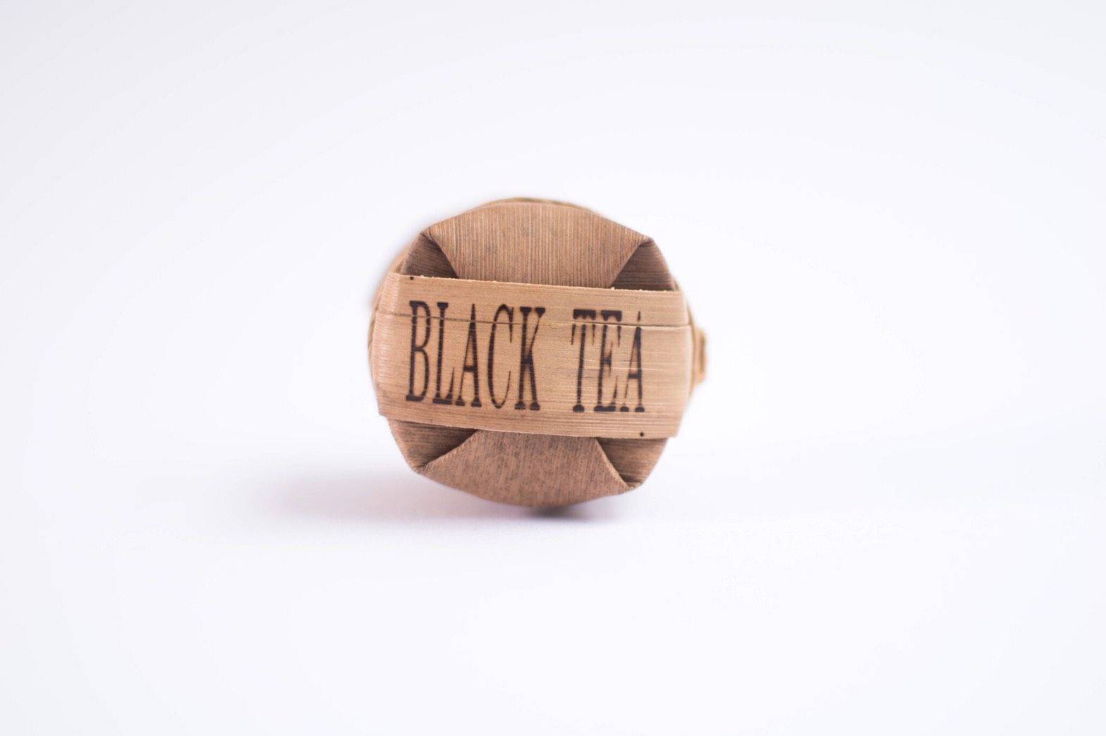 Round, compressed block of black tea, wrapped in paper, with