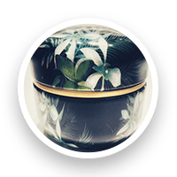 Round, black container decorated with white and green floral design.