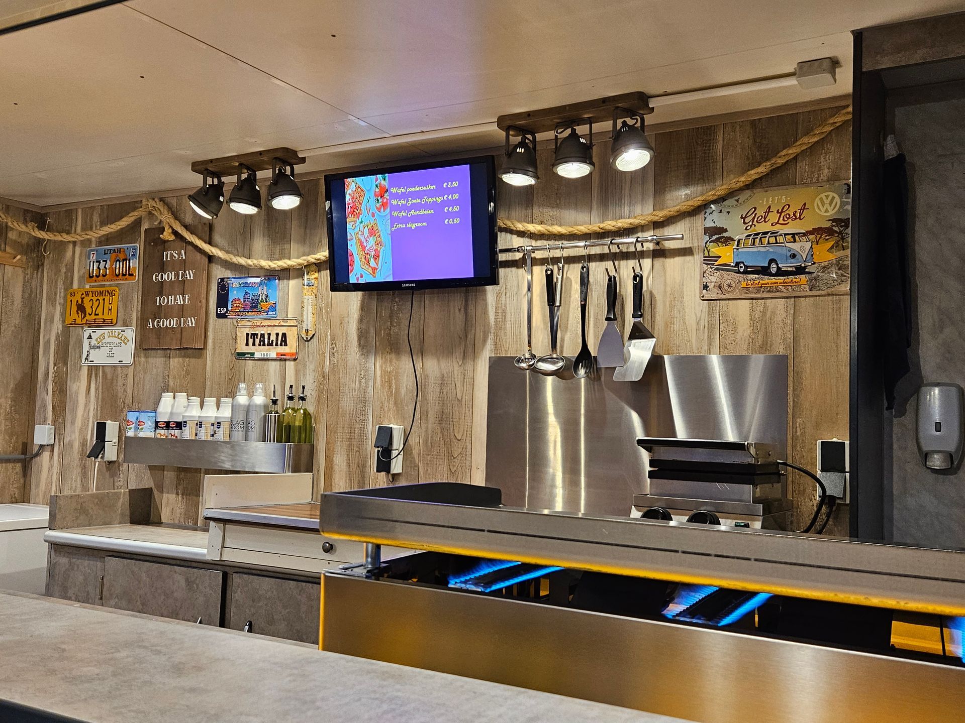 De toonbank van een restaurant is voorzien van roestvrij staal, houten lambrisering, een tv en decoratief touw.