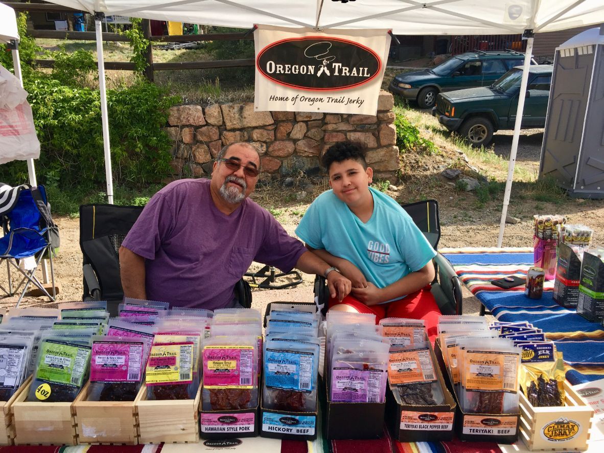 A man and a boy are sitting at a table with boxes of food.