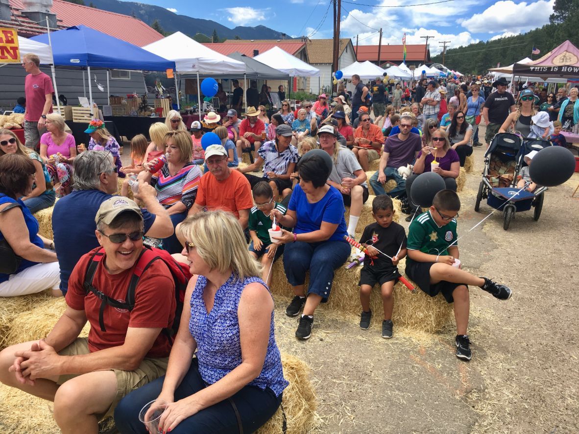 A crowd of people are sitting on hay bales at a festival.