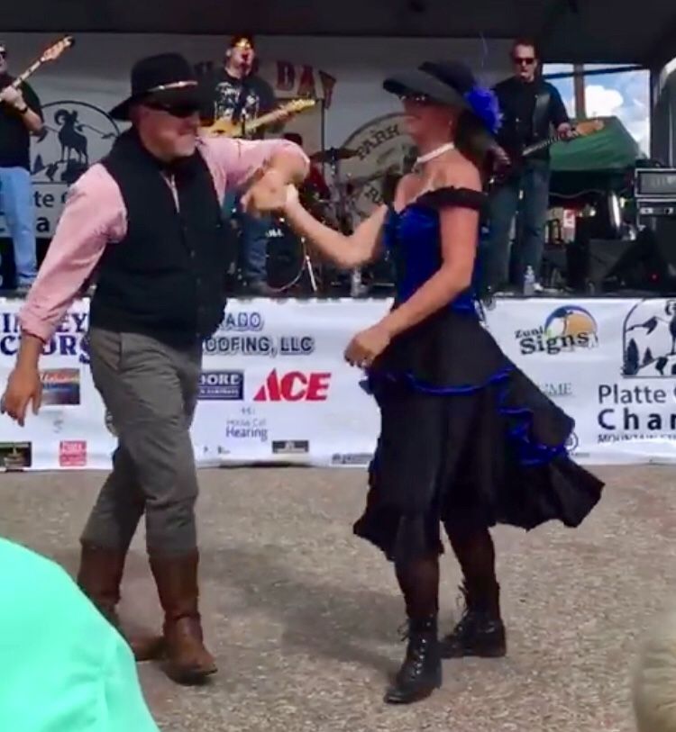 A man and a woman are dancing in front of a banner that says ace