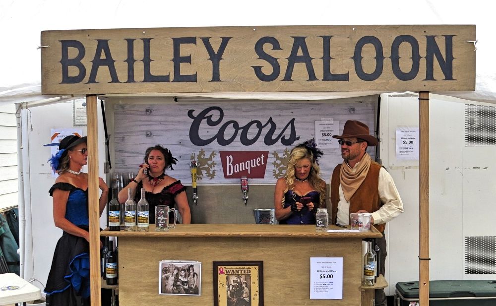 A group of people standing behind a bar under a sign that says bailey saloon.