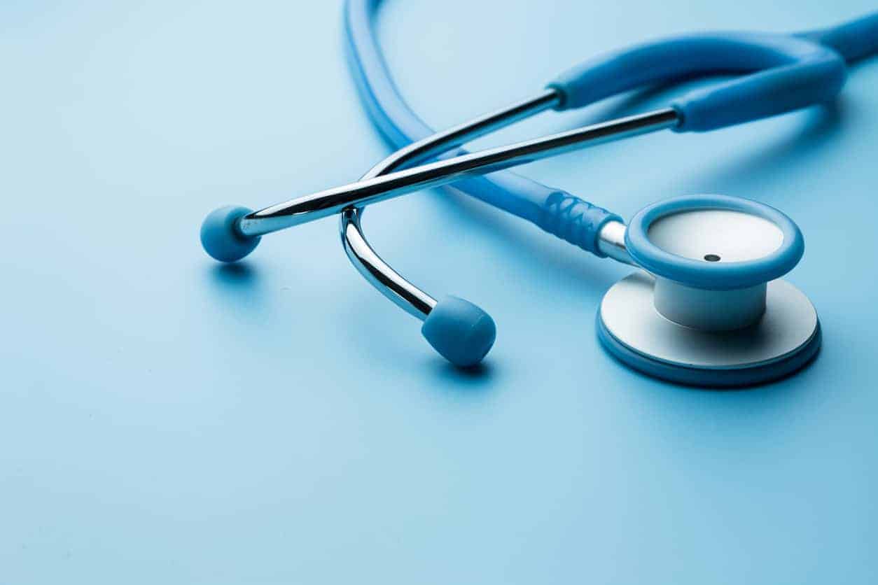 A blue stethoscope is sitting on a blue surface.