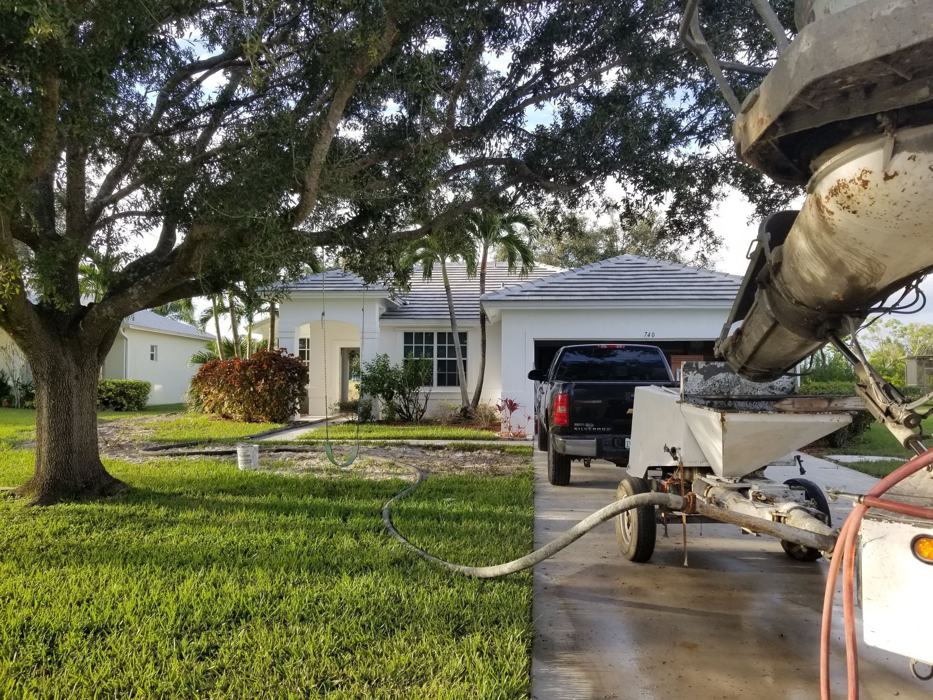 A truck is parked in front of a house with a concrete pump in the driveway.