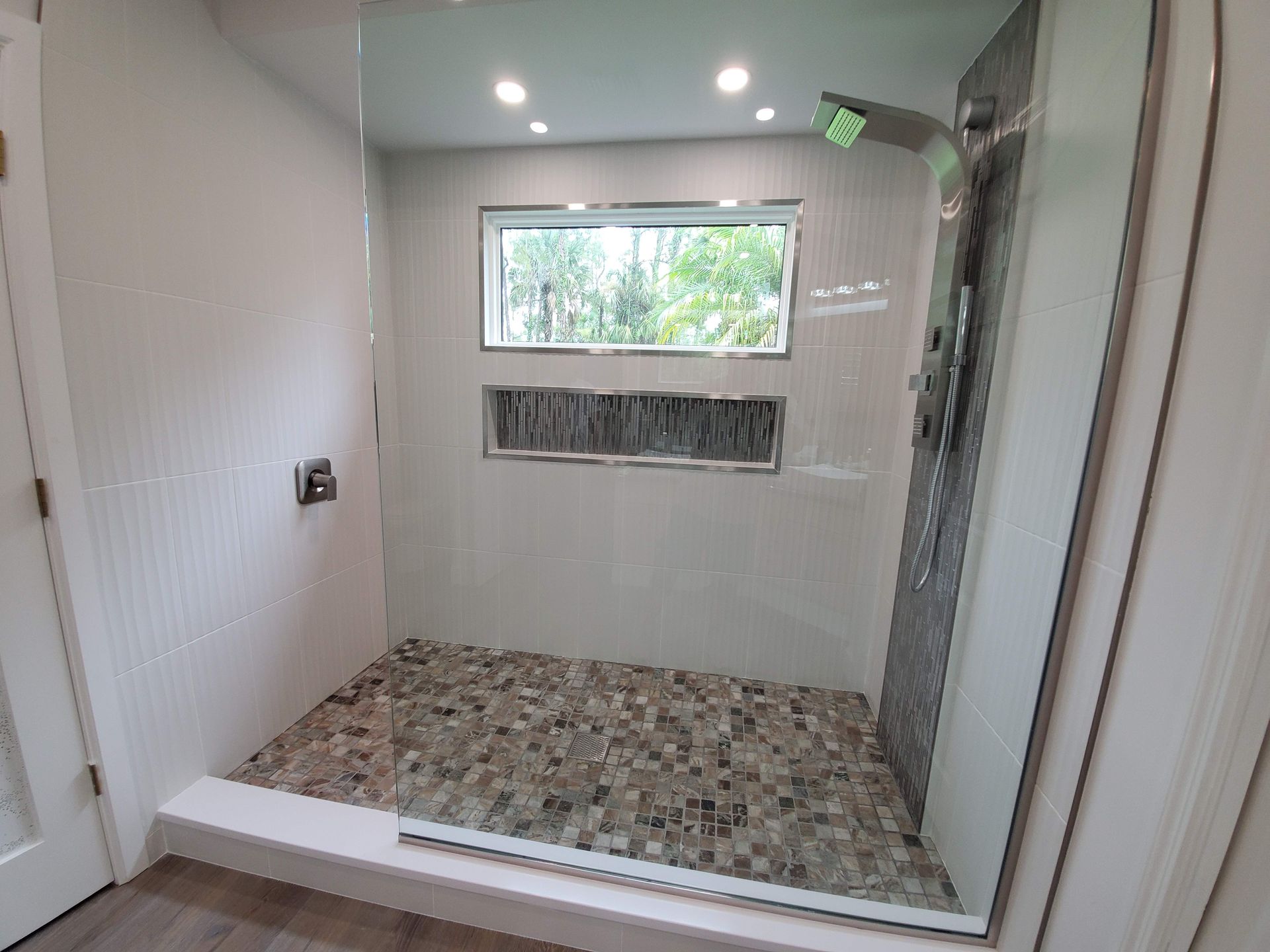 A bathroom with a walk in shower and a window.