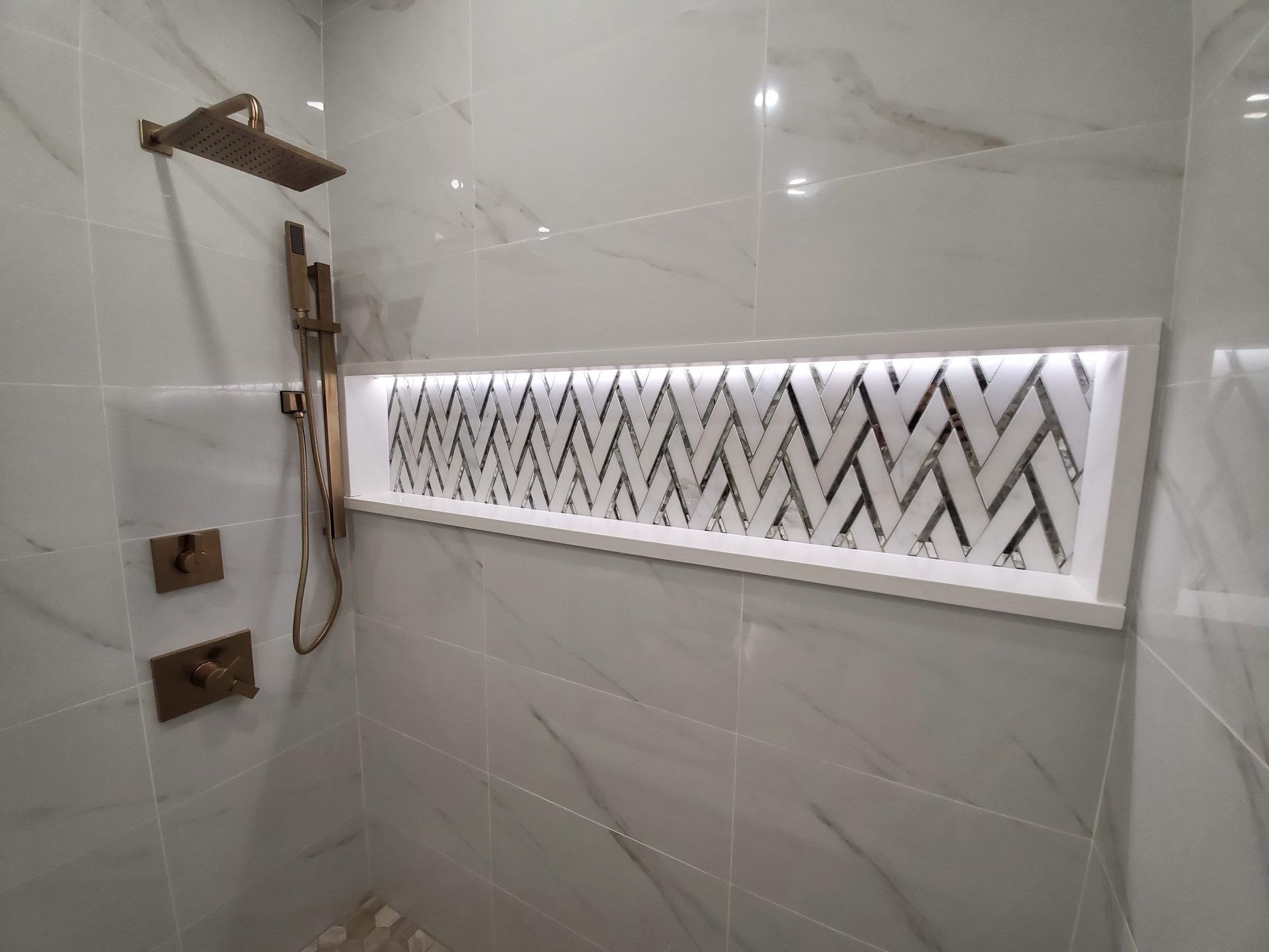 A bathroom with a shower head and a shelf with a pattern on it.