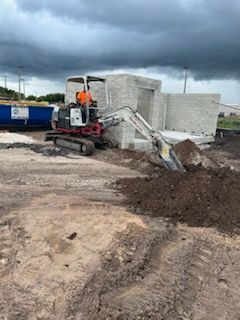 An excavator is digging a hole in the dirt on a construction site.