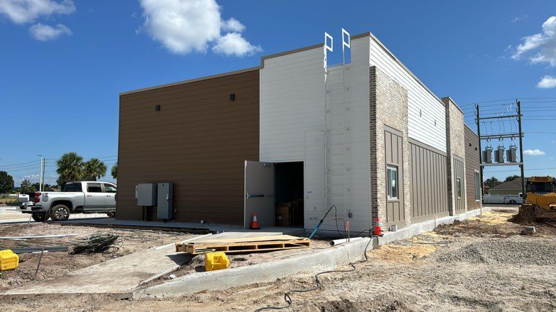 A building is being built in a dirt lot with a truck parked in front of it.