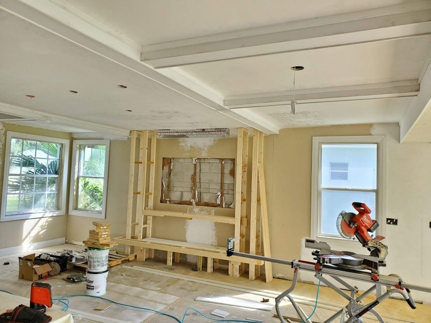 A living room under construction with a circular saw on the floor.