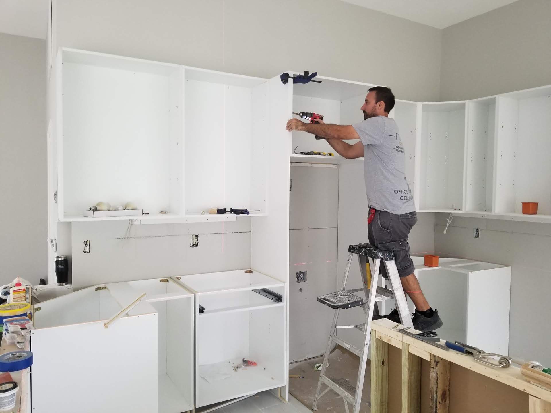 A man is standing on a ladder in a kitchen.