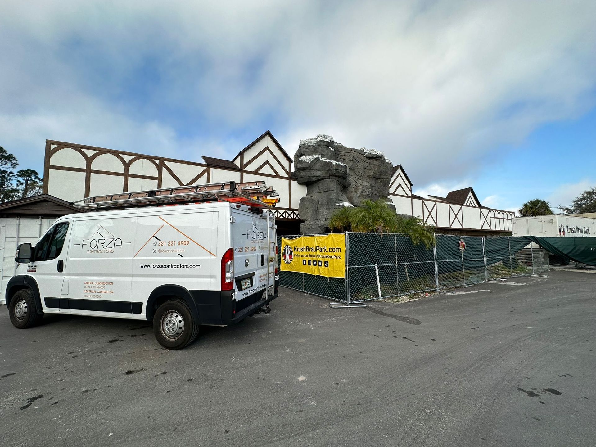 A white van with a ladder on top of it is parked in front of a building.
