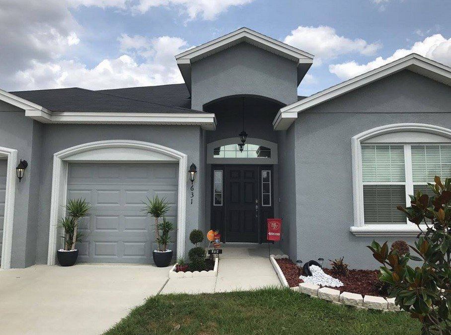 A gray house with a black door and a black garage door