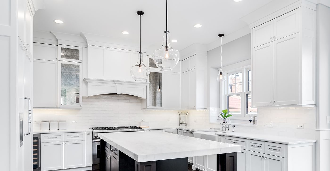 A kitchen with white cabinets and a large island in the middle.