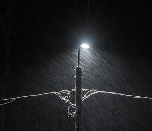 A street light is lit up in the snow at night