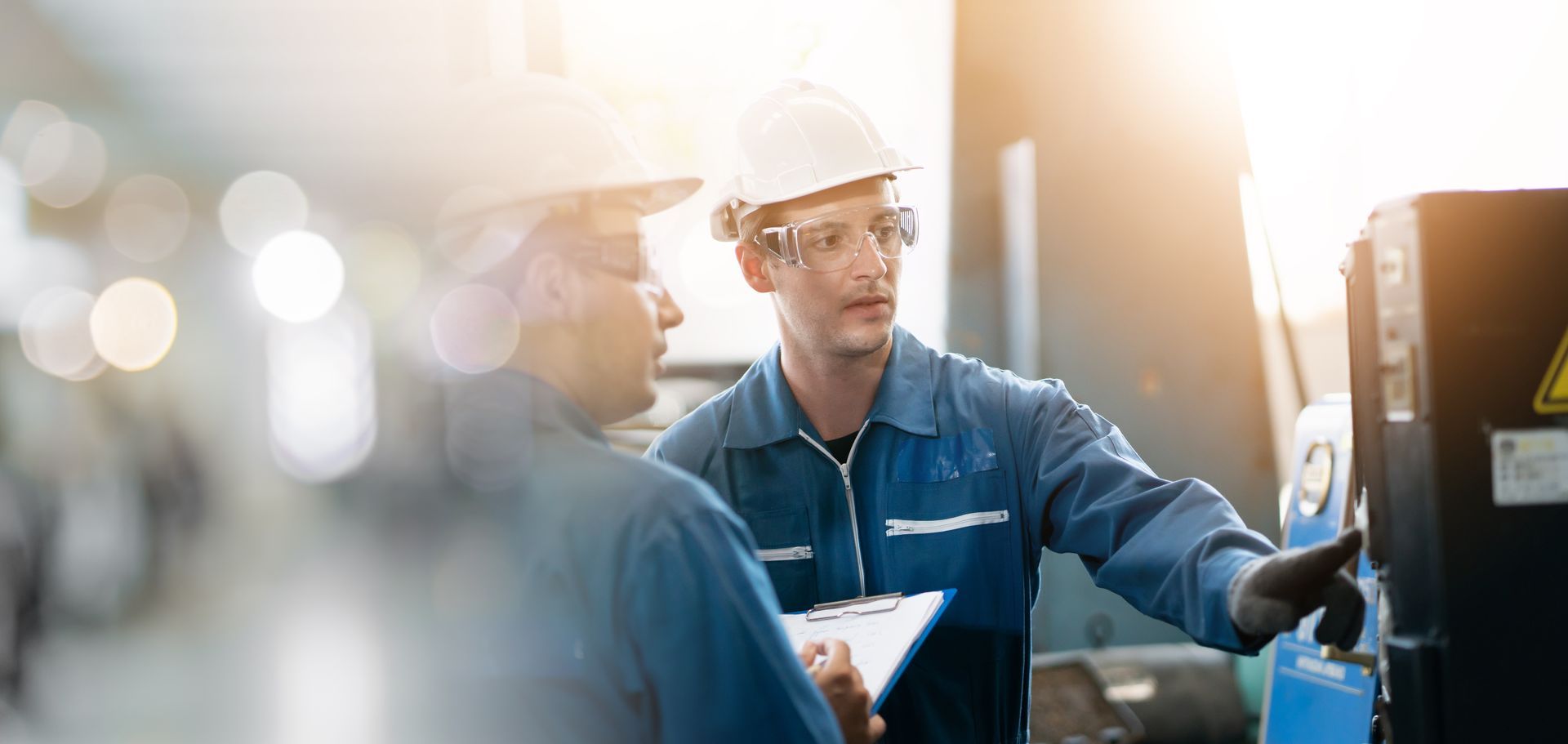 Two men are working on a machine in a factory.