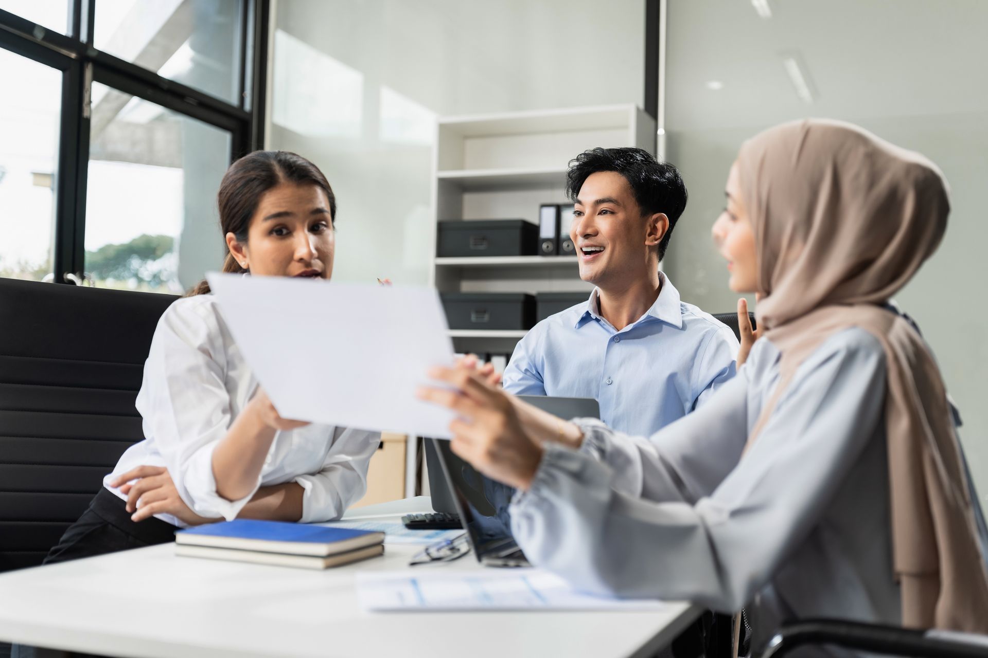 A group of people are sitting around a table looking at a piece of paper.