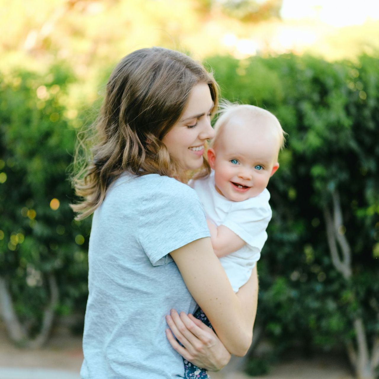 A woman is holding a baby in her arms and smiling.