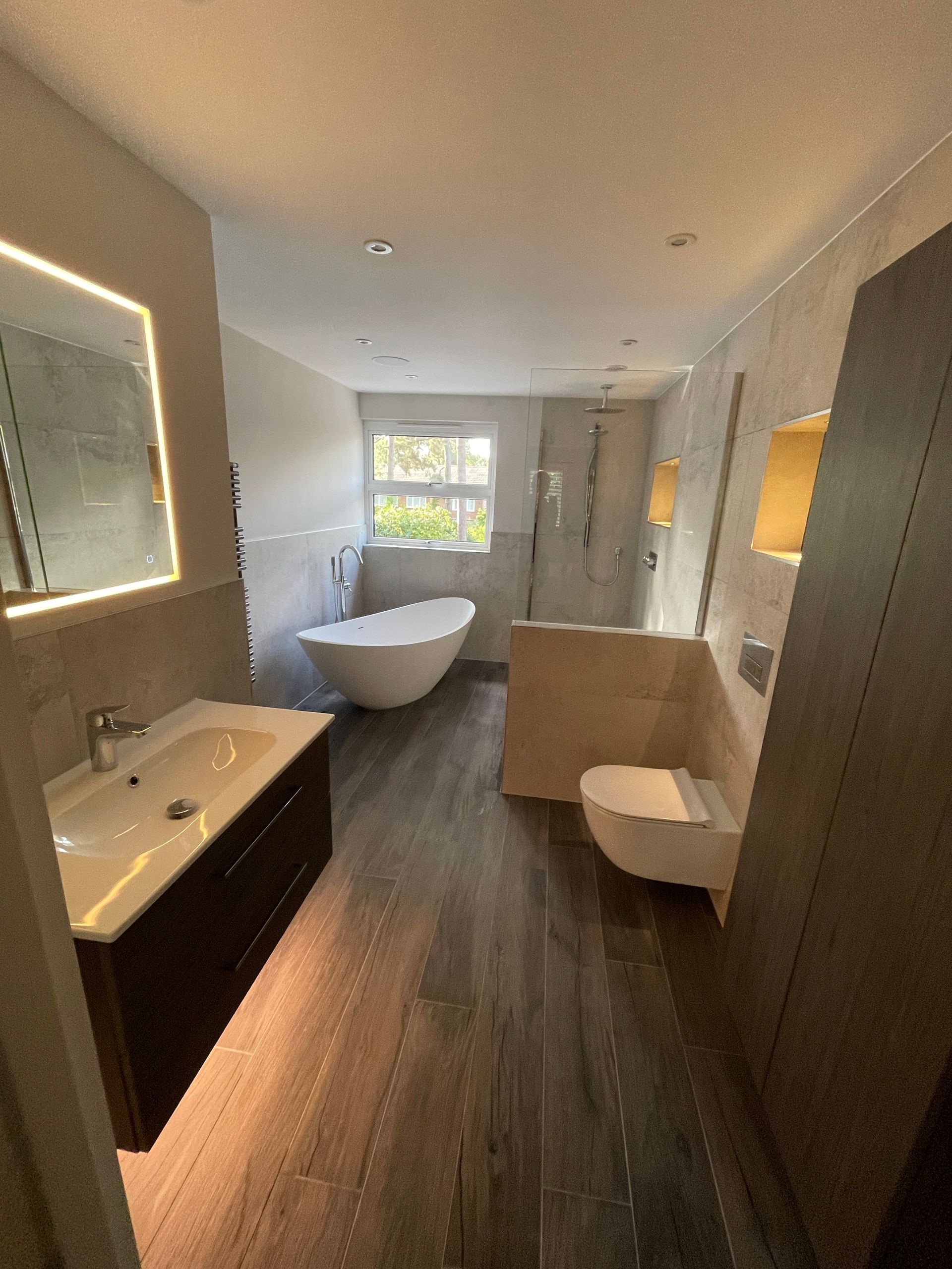 A luxury bathroom with a freestanding pedestal bath and large format tiles fitted by local bathroom fitters at Options Bath and Tile studio.