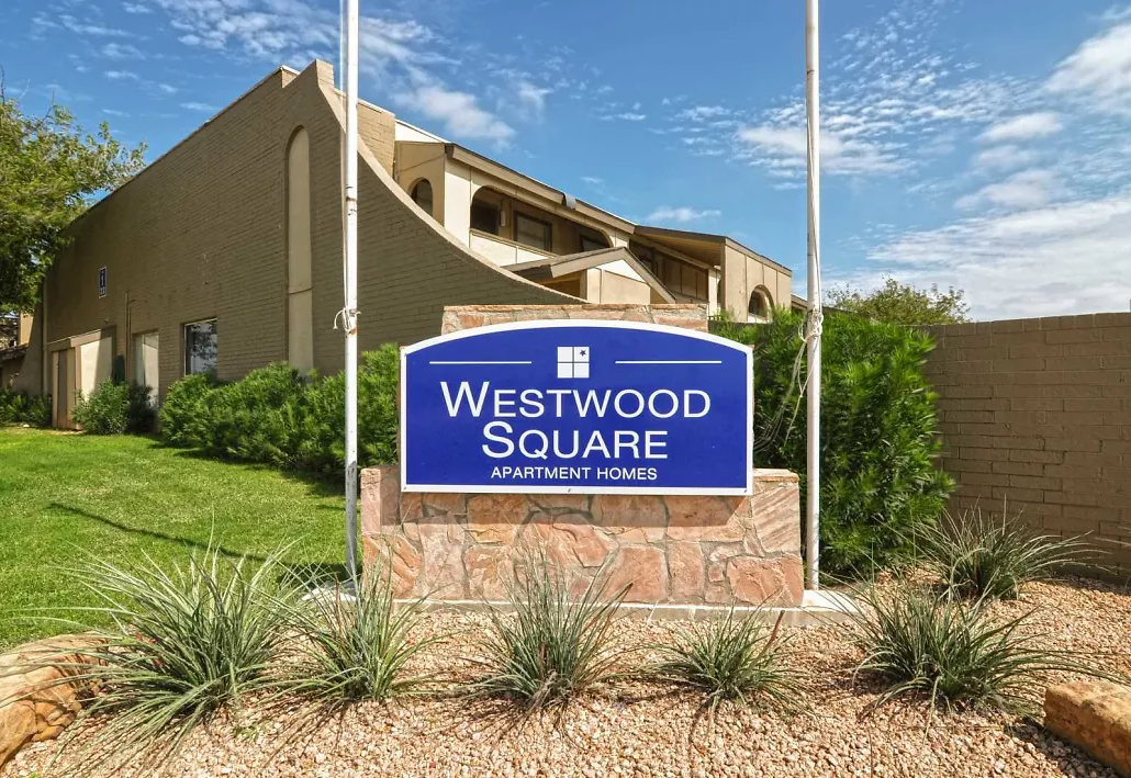 Blue Westwood Square Apartment Homes sign on a stone base with desert landscaping.