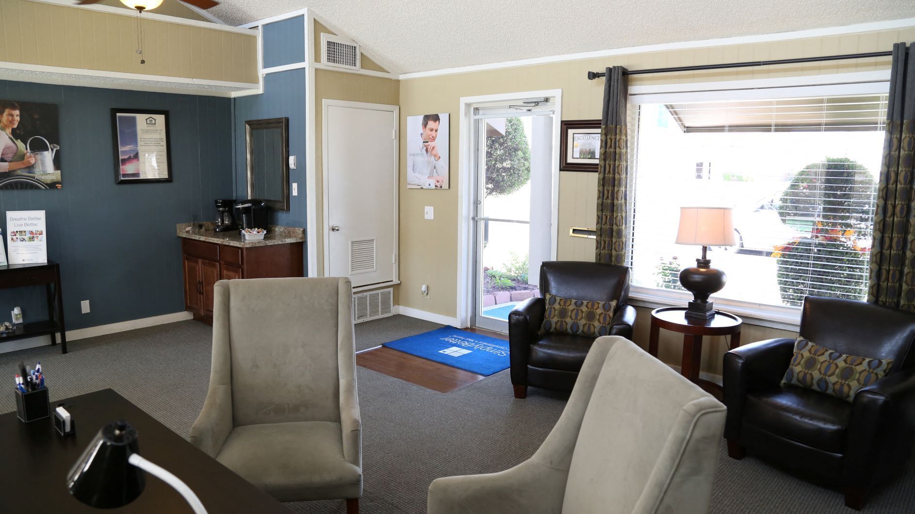 Waiting room with tan walls, seating, and a window.