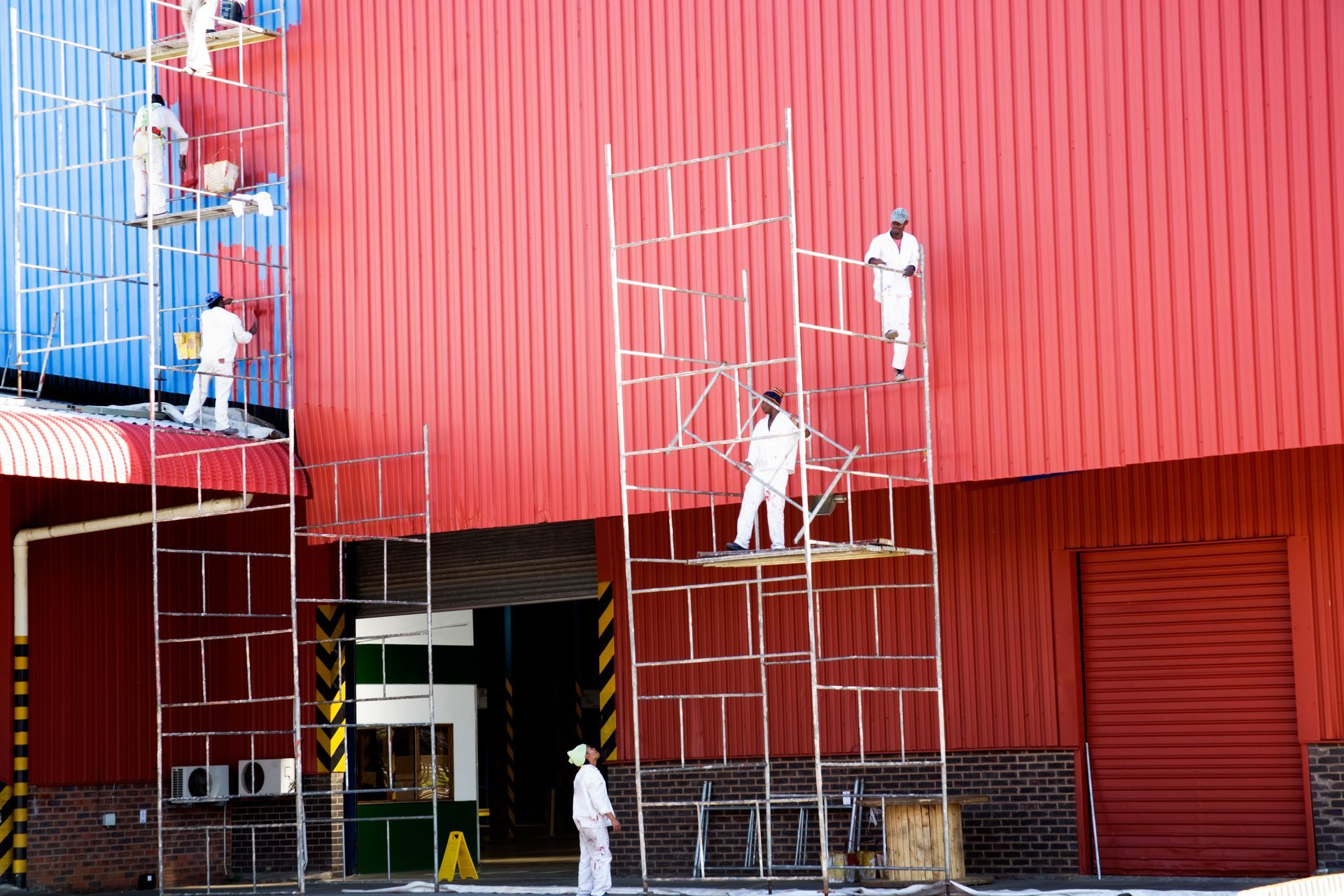 A group of people are painting a red building