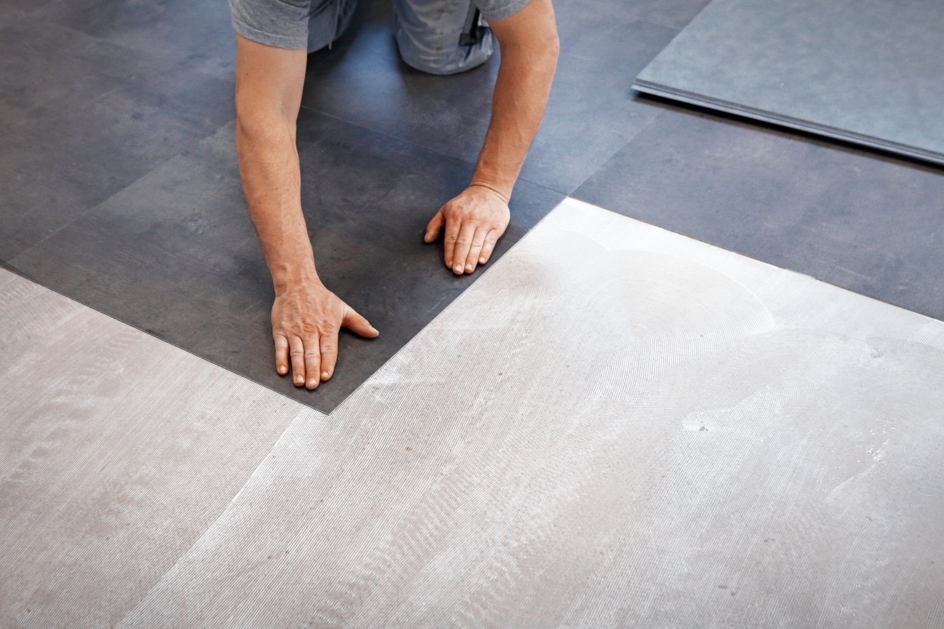 A man is installing a vinyl floor in a room.
