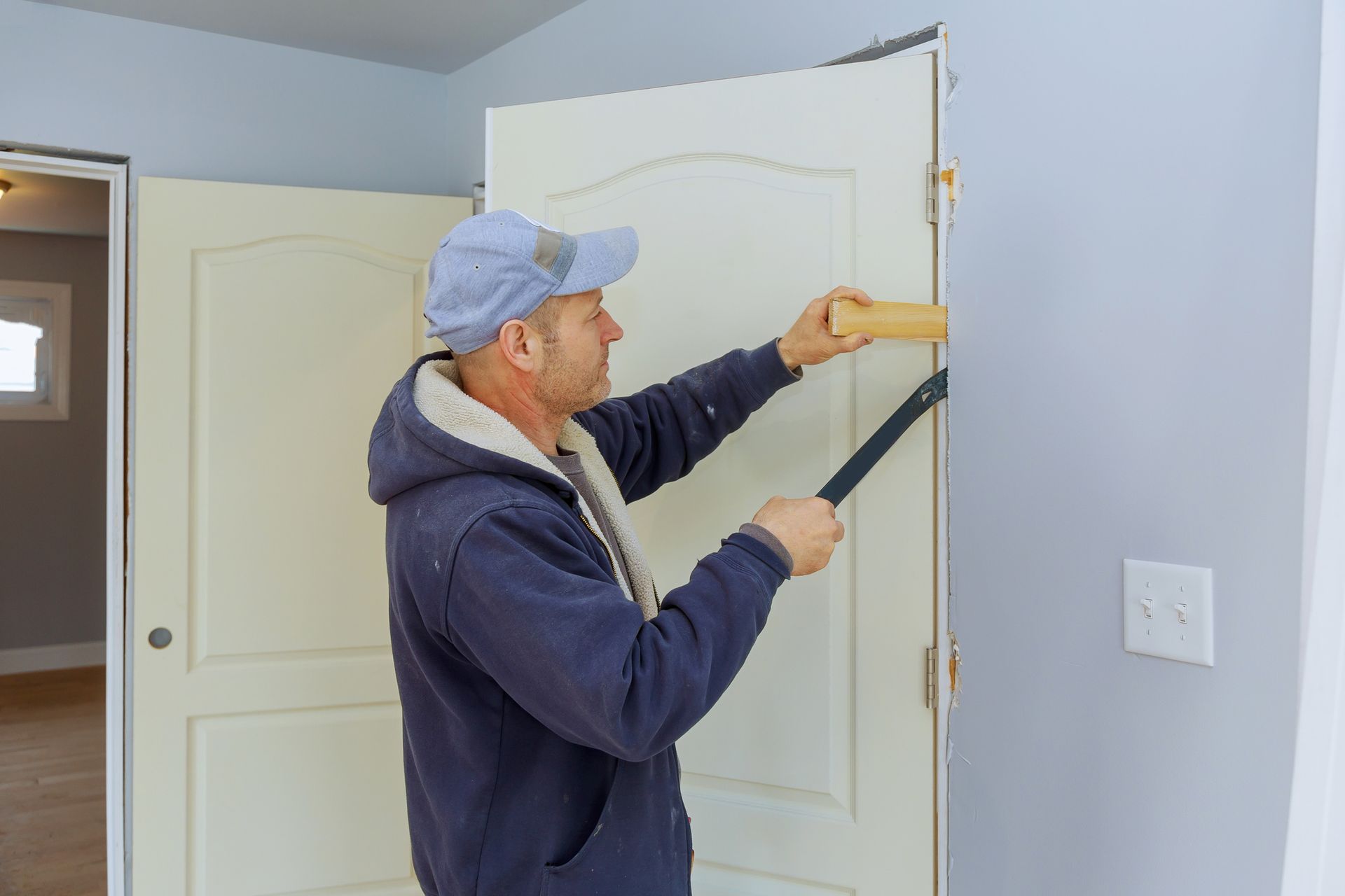 A man is installing a door in a room.