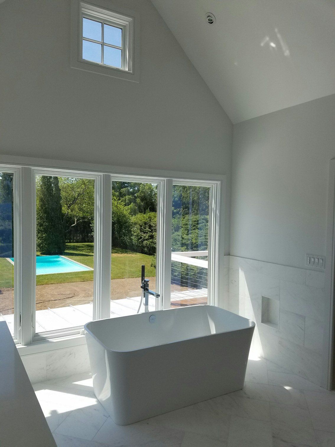 Bathroom remodel with a large white bathtub, marble floors and marble wall tiles