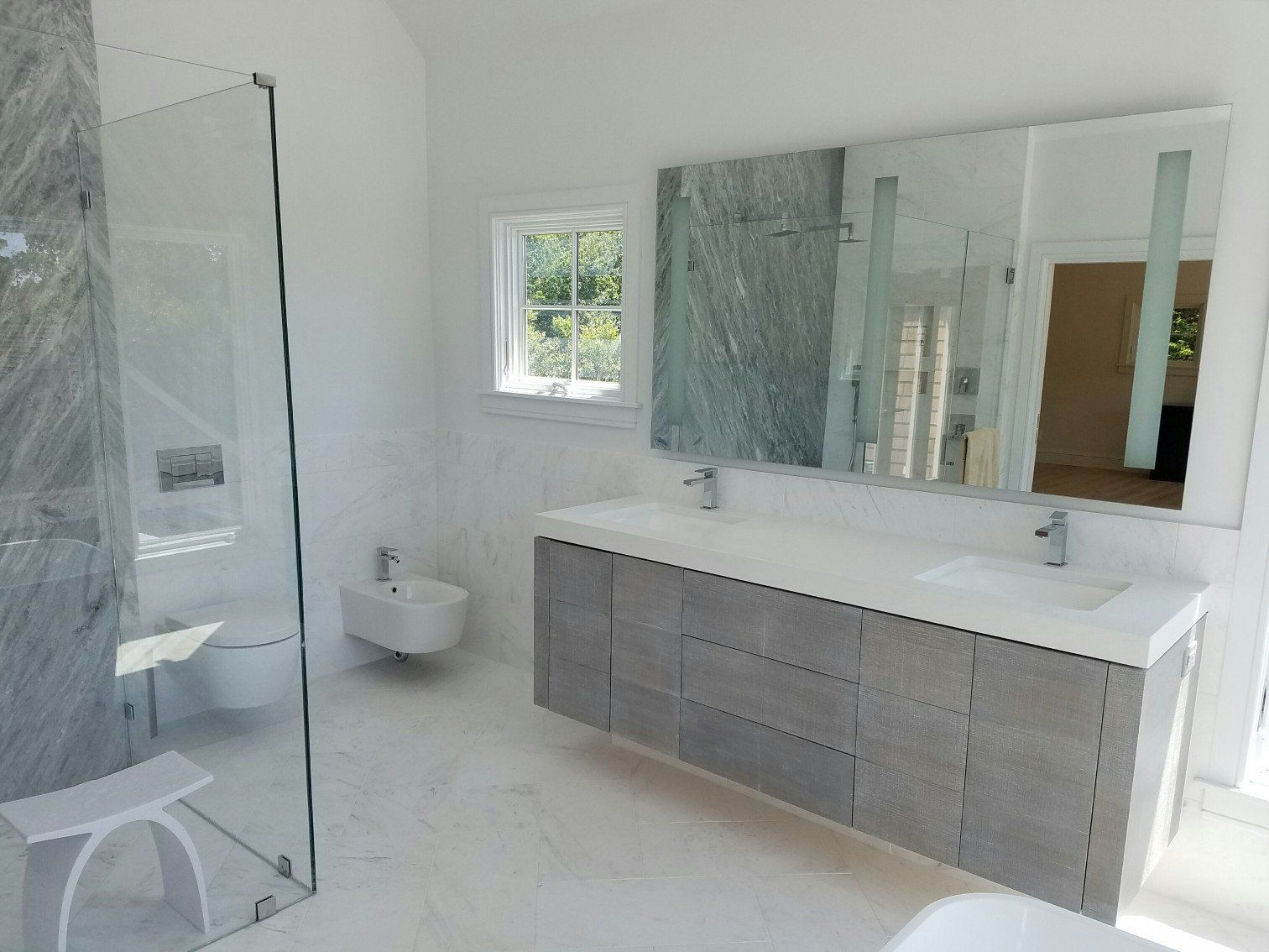 Master Bathroom remodel with gray his & hers sink, floating toilet, and marble floors