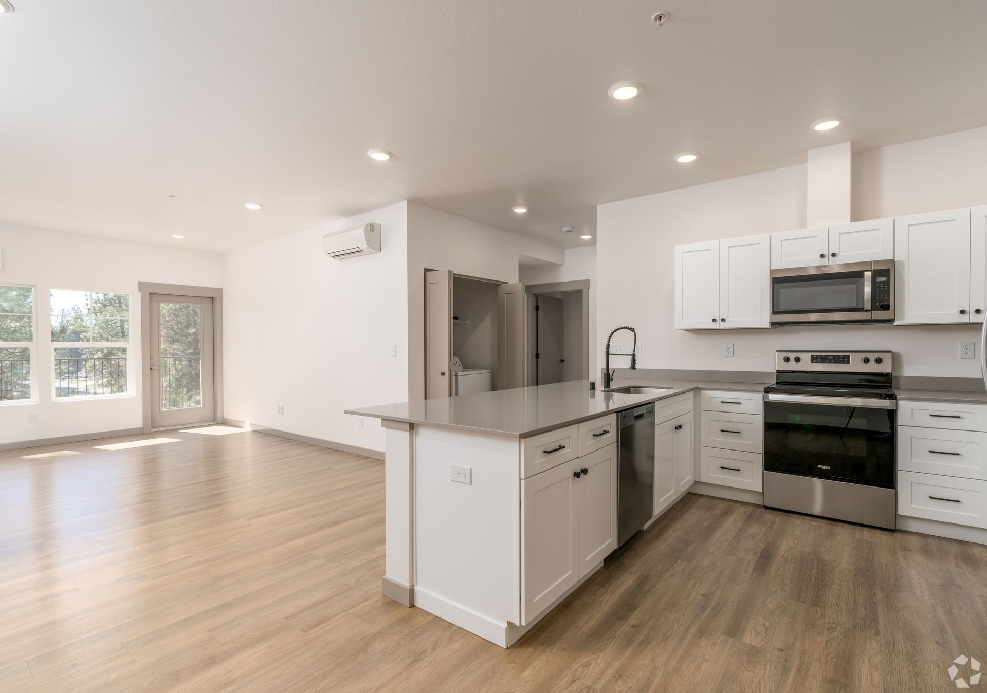 An empty kitchen with white cabinets and stainless steel appliances.