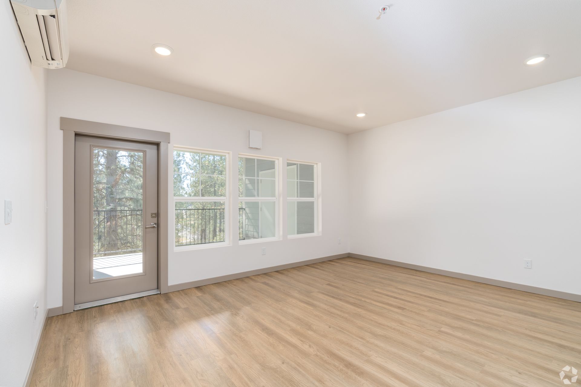 An empty living room with hardwood floors and a sliding glass door.