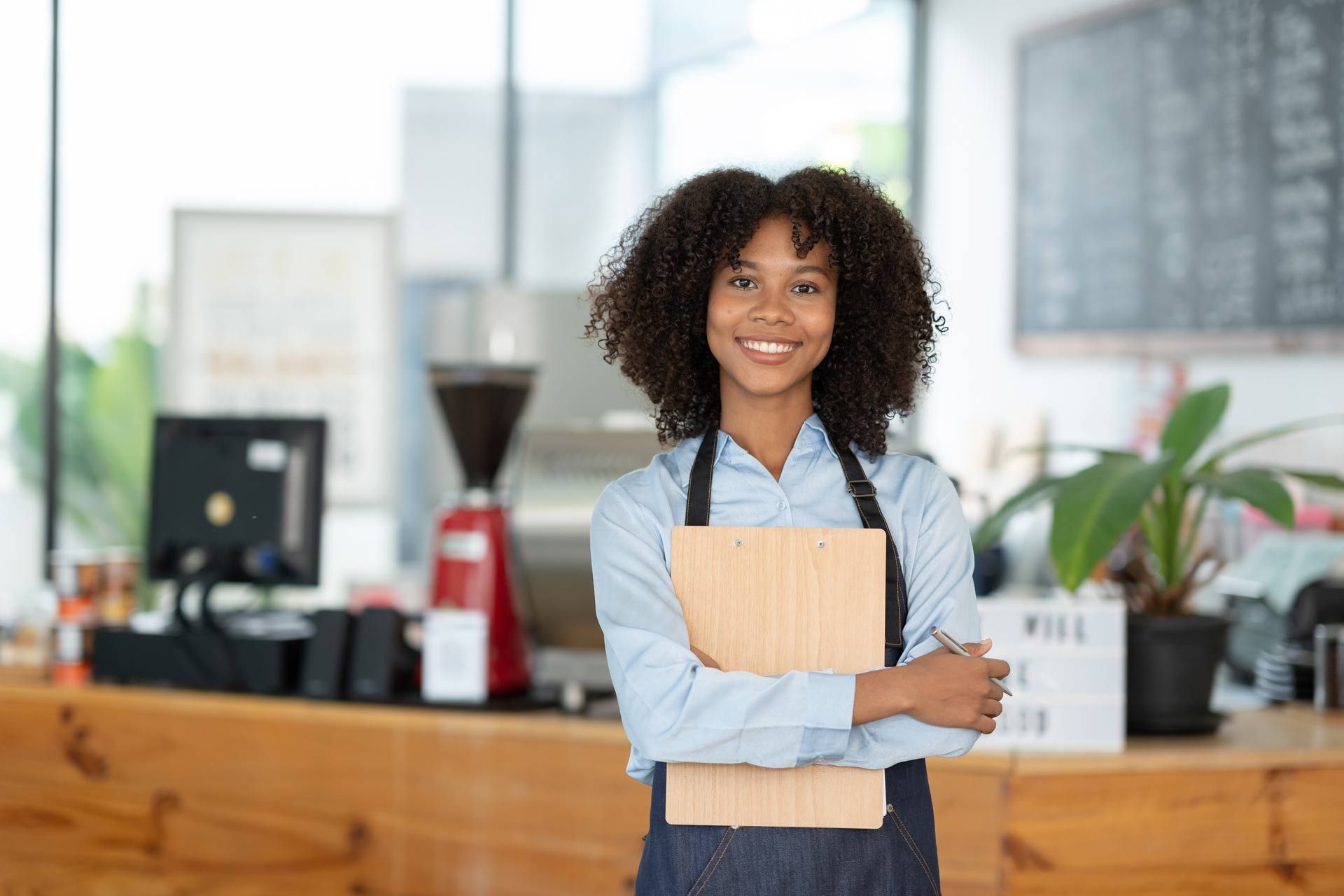 a woman in an apron is holding a clipboard and smiling