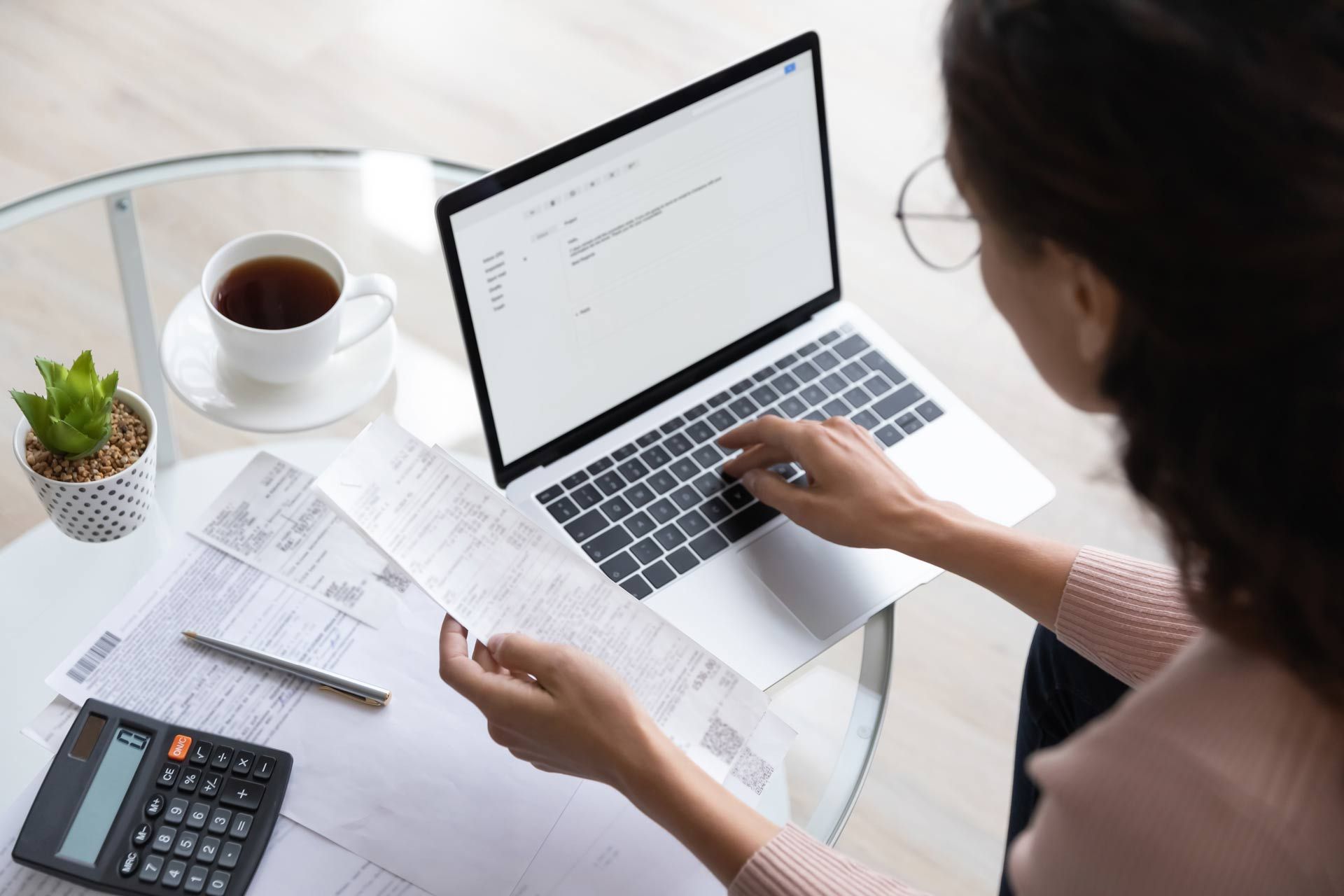 a woman sits at a desk with a laptop and a calculator