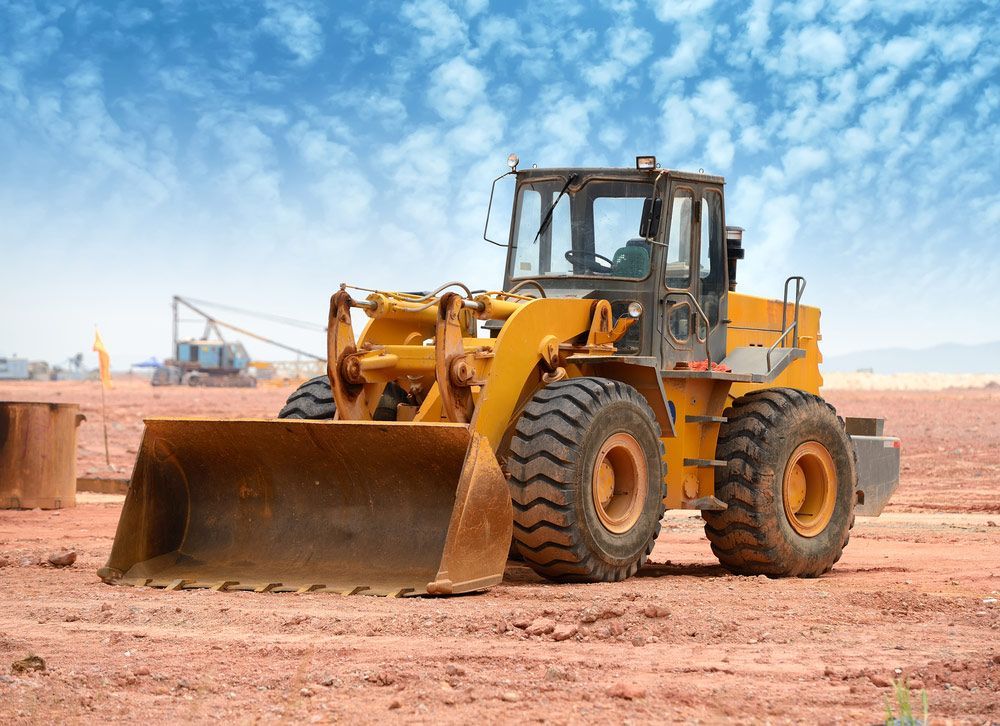 A Yellow Bulldozer is Parked in a Dirt Field — JTM Projects Australia Pty Ltd in Mackay, QLD