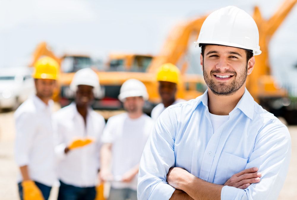 A Man Wearing A Hard Hat Is Standing In Front Of A Group Of Construction Workers — JTM Projects Australia Pty Ltd in Townsville, QLD
