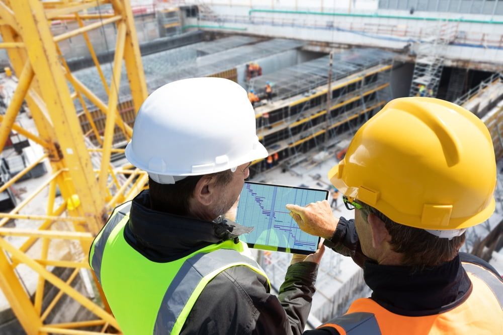 Two Construction Workers Are Looking At A Tablet At A Construction Site — JTM Projects Australia Pty Ltd in Emerald, QLD