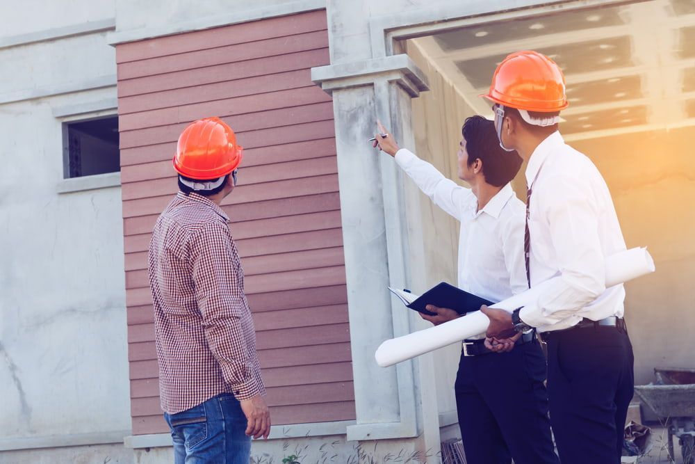 A Group Of Construction Workers Are Standing In Front Of A Building Under Construction — JTM Projects Australia Pty Ltd in Moranbah, QLD