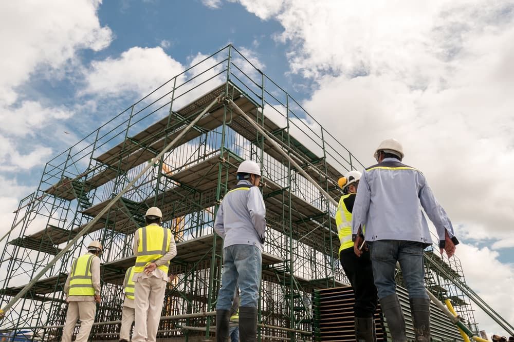 A Group Of Construction Workers Are Standing On Top Of A Building Under Construction — JTM Projects Australia Pty Ltd in Brisbane, QLD