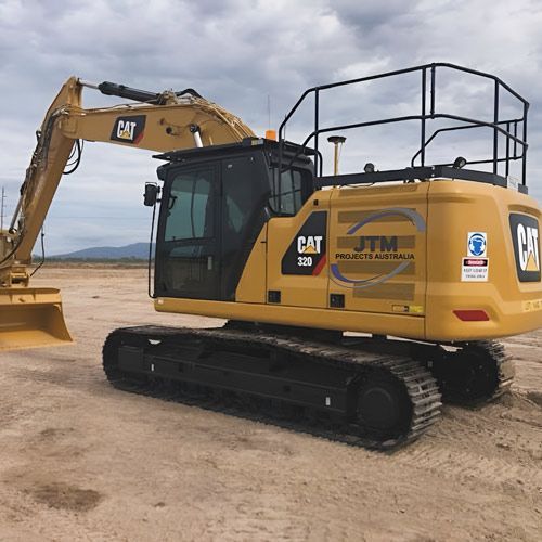 A Yellow Cat Excavator is Parked in a Dirt Field — JTM Projects Australia Pty Ltd in Hollywell, QLD