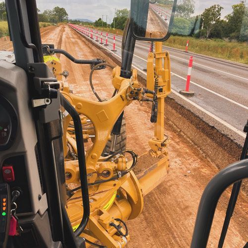 A Yellow Tractor is Working on the Side of a Road — JTM Projects Australia Pty Ltd in Hollywell, QLD