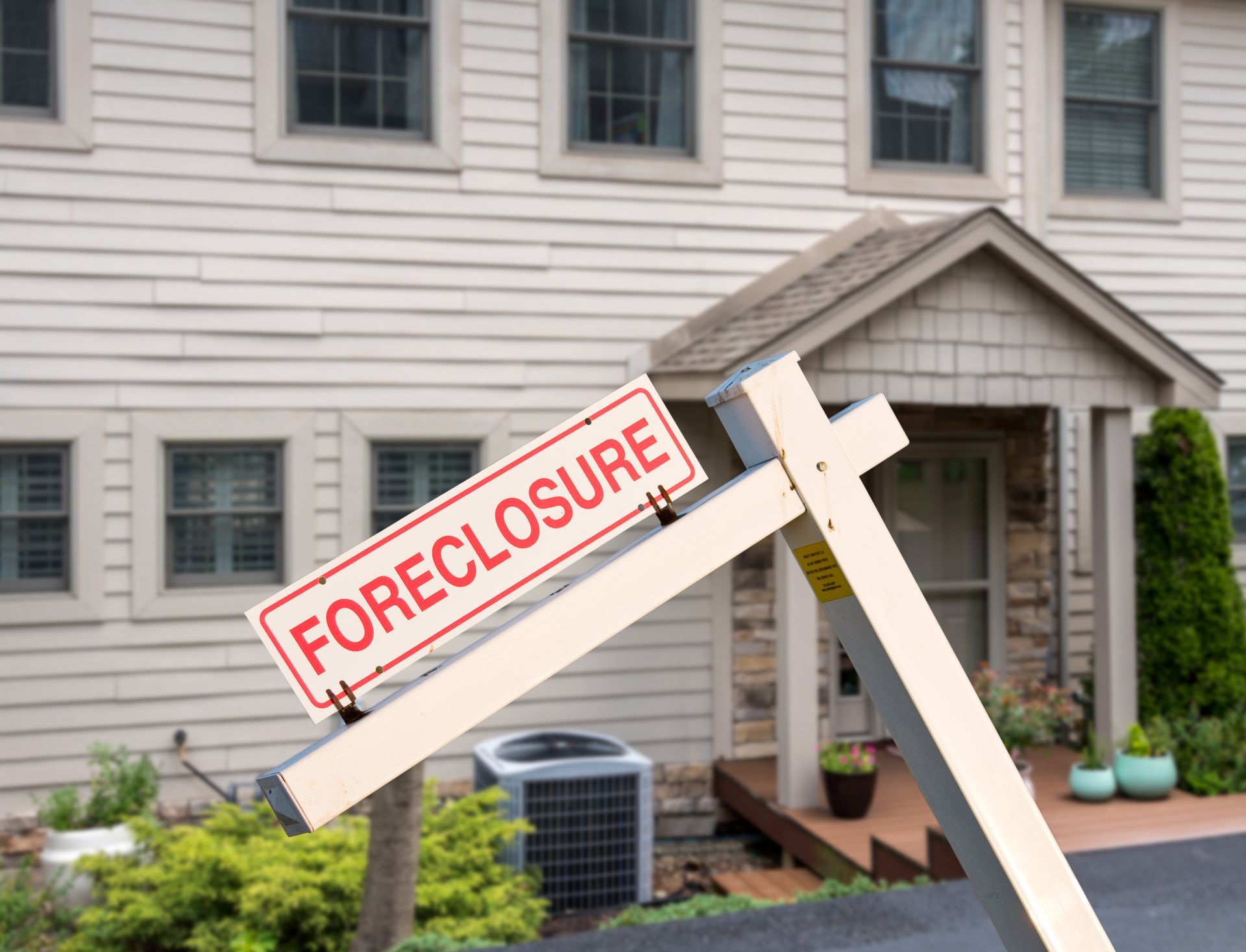 Sign reading FORECLOSURE in front of a house.