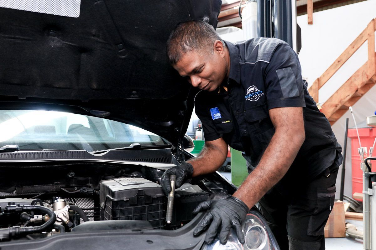 A man is working on a car on a lift in a garage.
