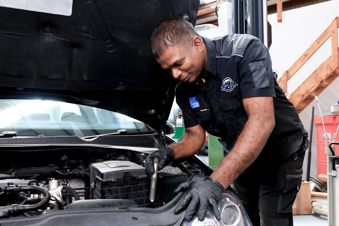 A man is working on a car on a lift in a garage.