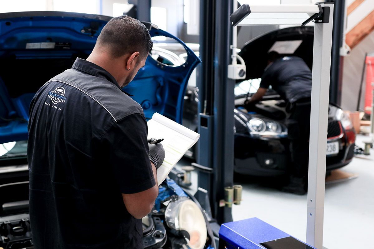 Two men are looking at a clipboard in front of a blue truck.